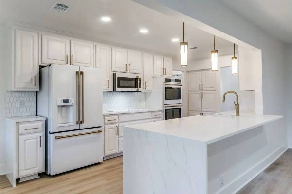 Modern kitchen remodel with white shaker cabinets, gold hardware, and a quartz waterfall island